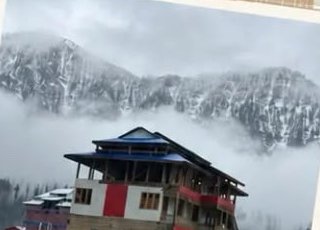 Wooden house in front of misty snow-covered mountains at Arang Kel