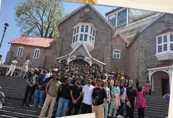 A large group of QuadraTravels travellers on the steps of a stone building in Murree